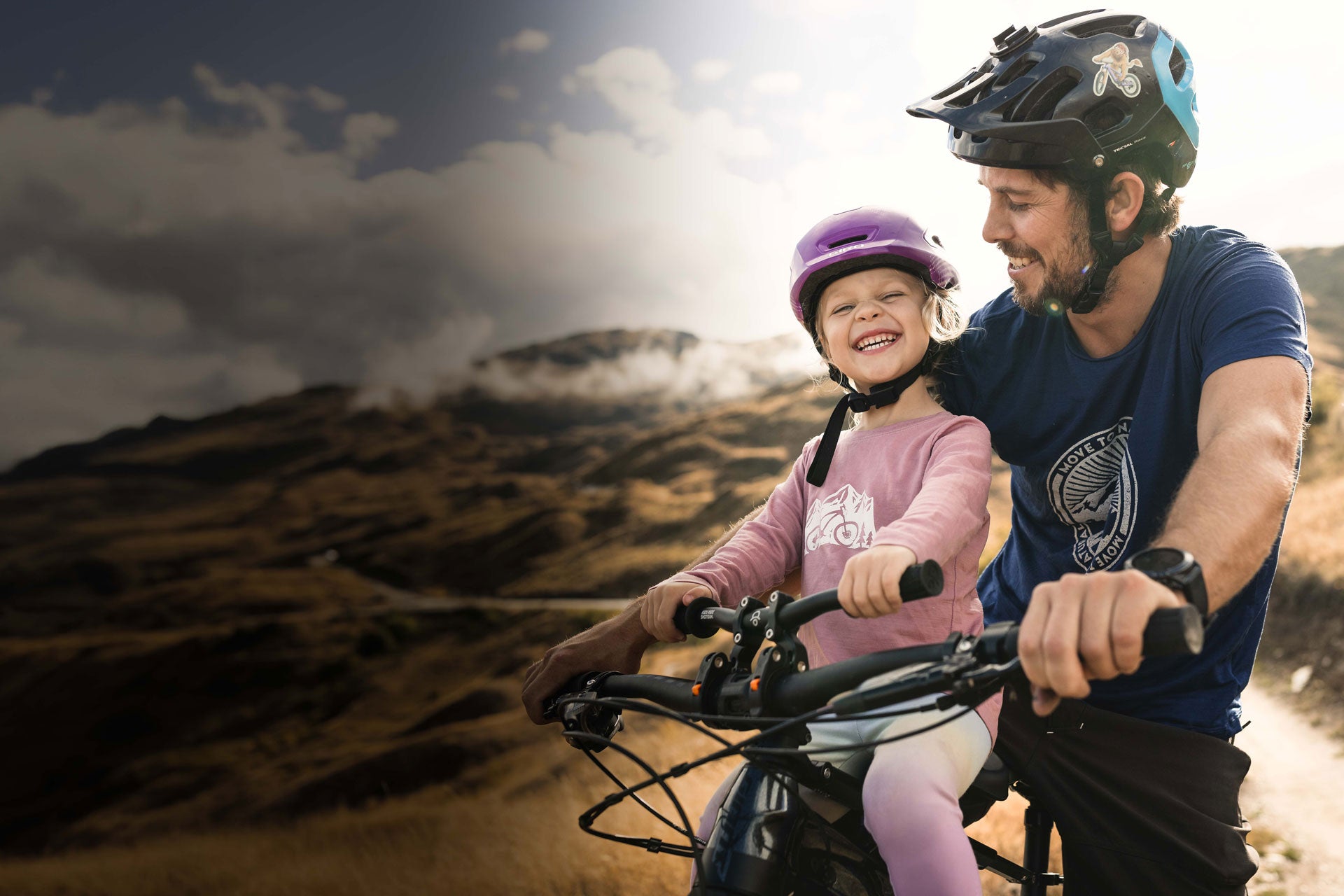 Man and child on a bike ride with mountains in the background